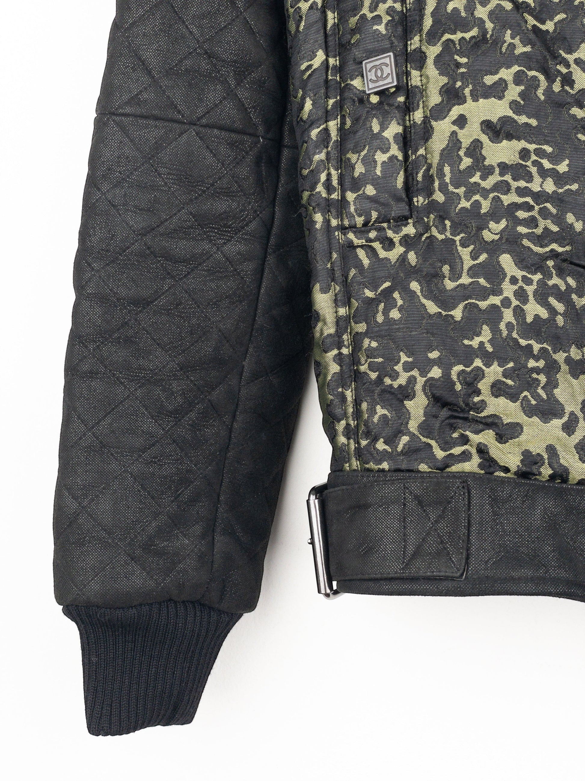 opening act. Chanel Bomberjacke mit Camouflage-Muster, gesteppten schwarzen Ärmeln und Schnallendetails an der Taille.